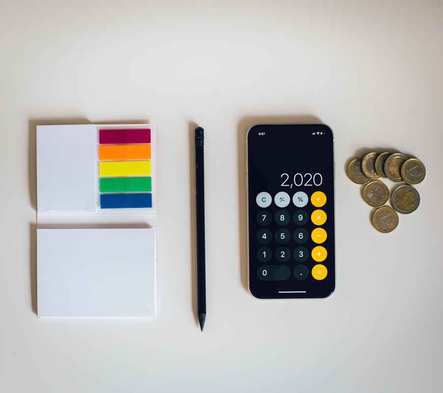 Picture of calculator, coins, notepad and pencil